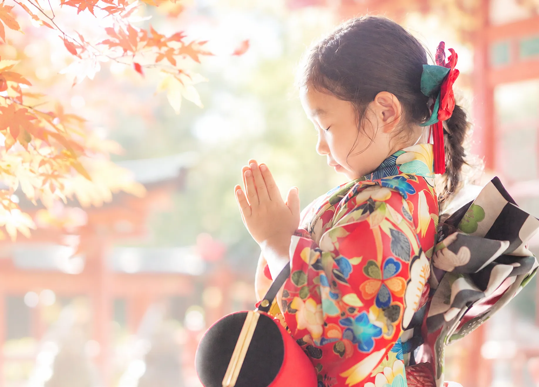 神社の境内で、着物姿の両親と袴姿の男の子が手をつないで歩く様子